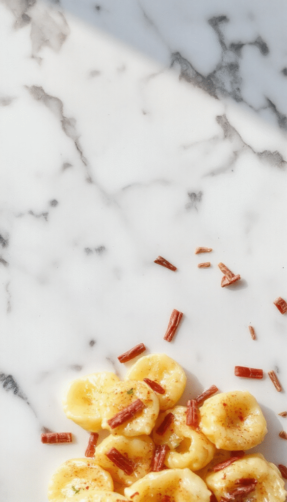 A vibrant plate of Marry Me Tortellini featuring golden-brown tortellini coated in a creamy sauce, garnished with fresh basil leaves, served on a rustic white plate with a colorful background and a sprig of herbs.